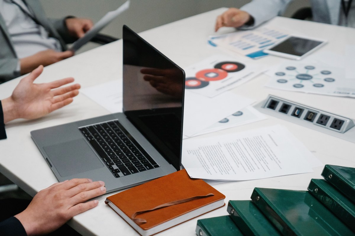 People discussing documents and a laptop around a meeting table